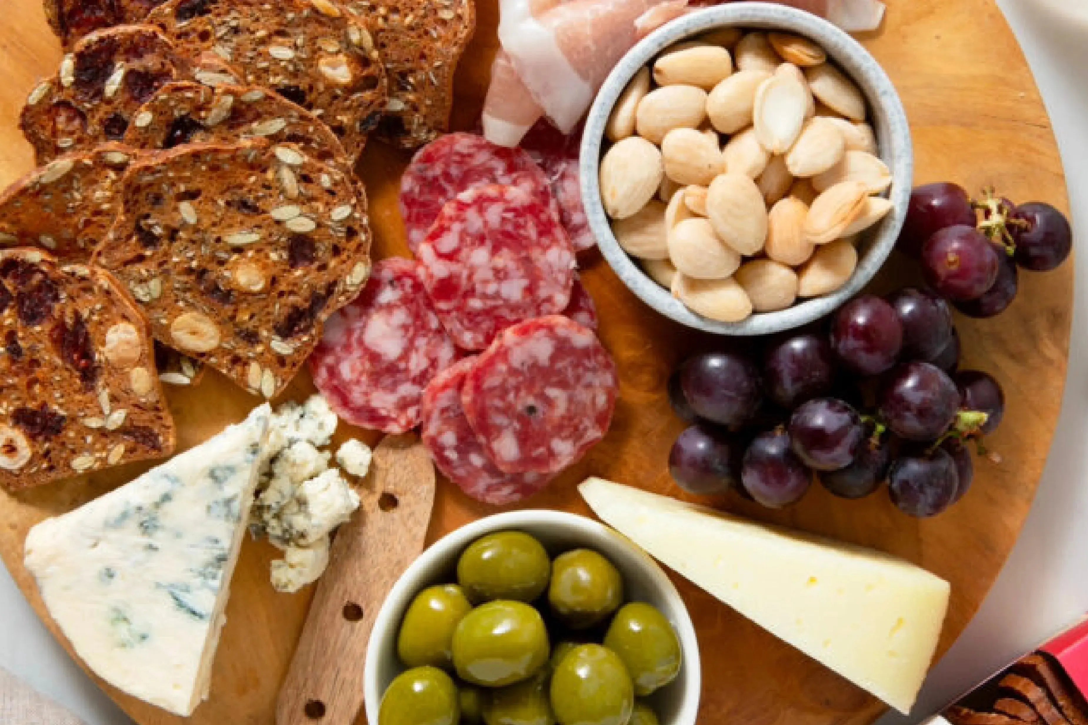 Charcuterie board with assorted cheeses, cured meats, crackers, fruit, and nuts.