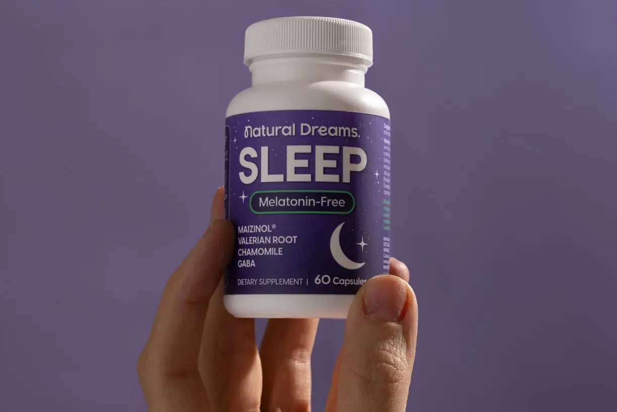 Person holding a Natural Dreams® melatonin-free sleep support supplement bottle.
