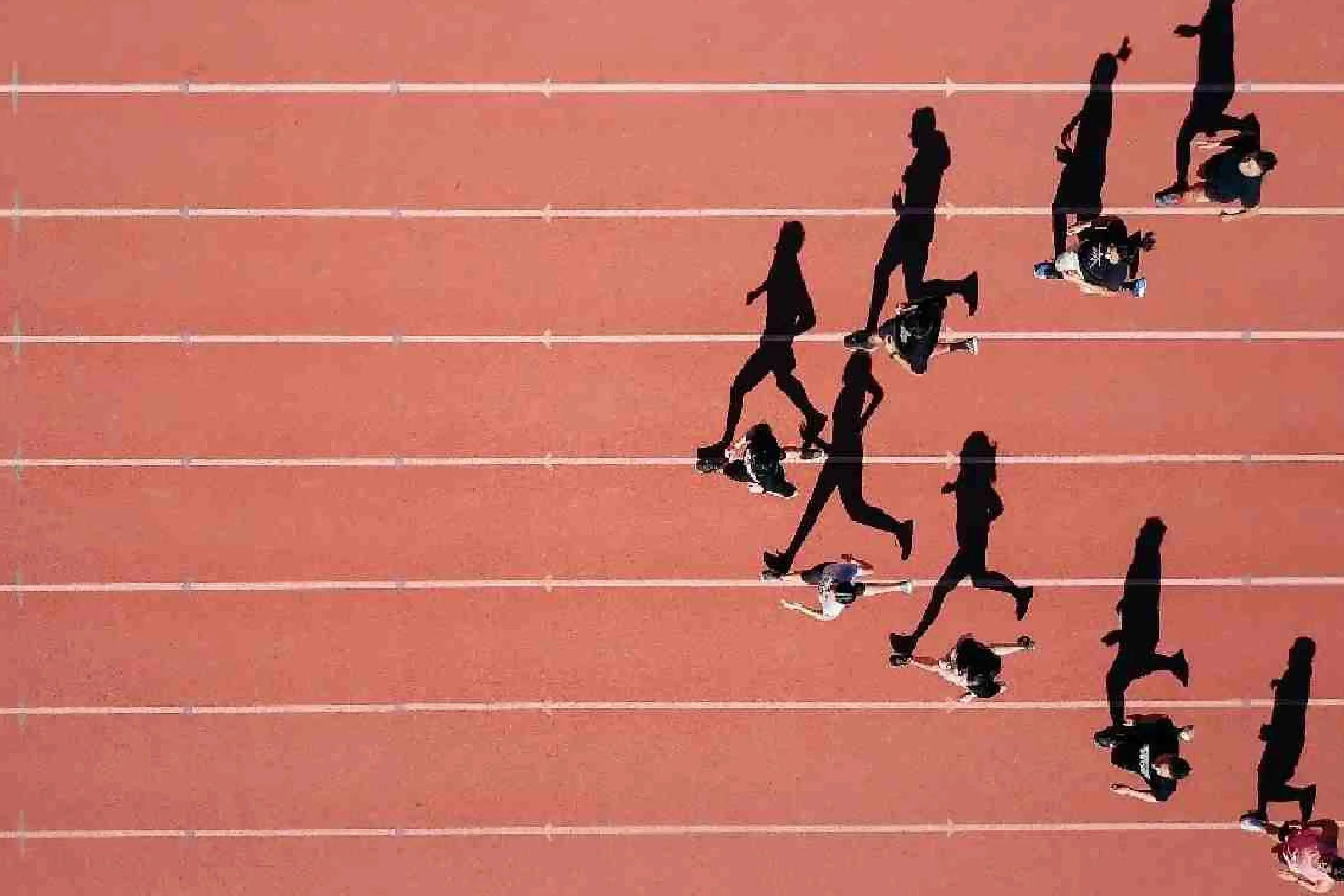 Group of people running on an outdoor track during a workout.