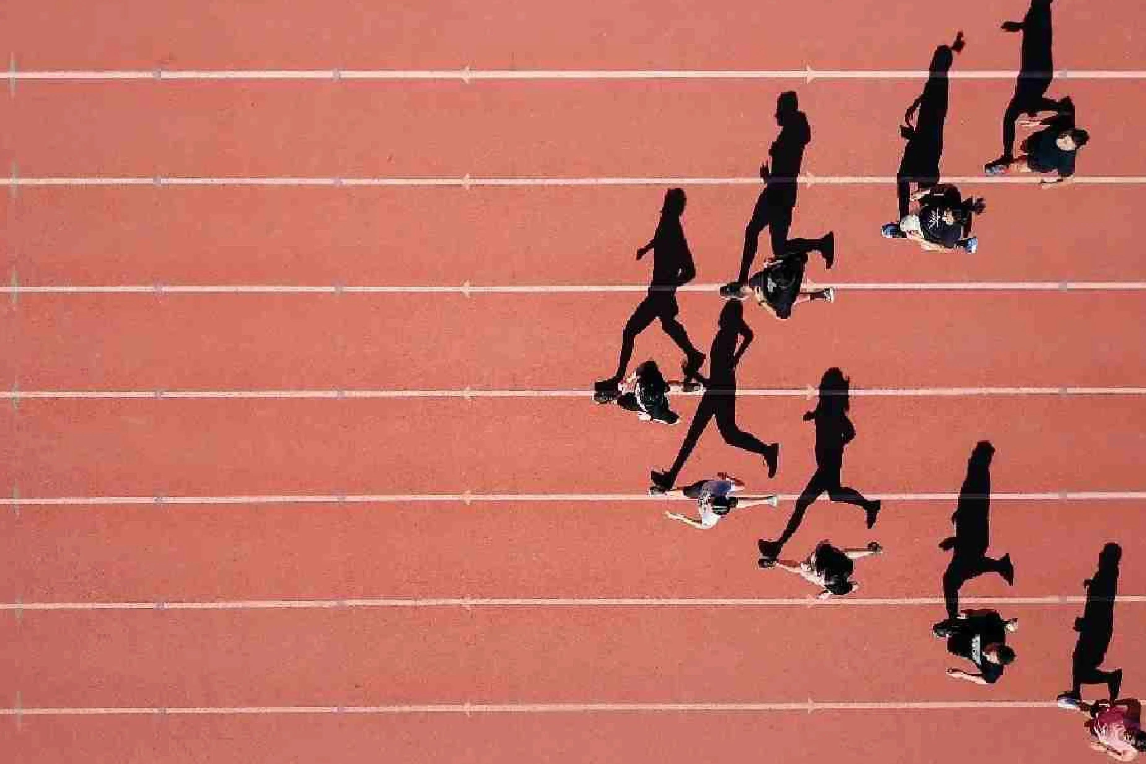 Group of people running on an outdoor track during a workout.