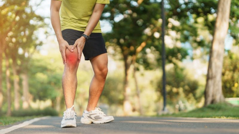 Man holding his knee while walking outdoors