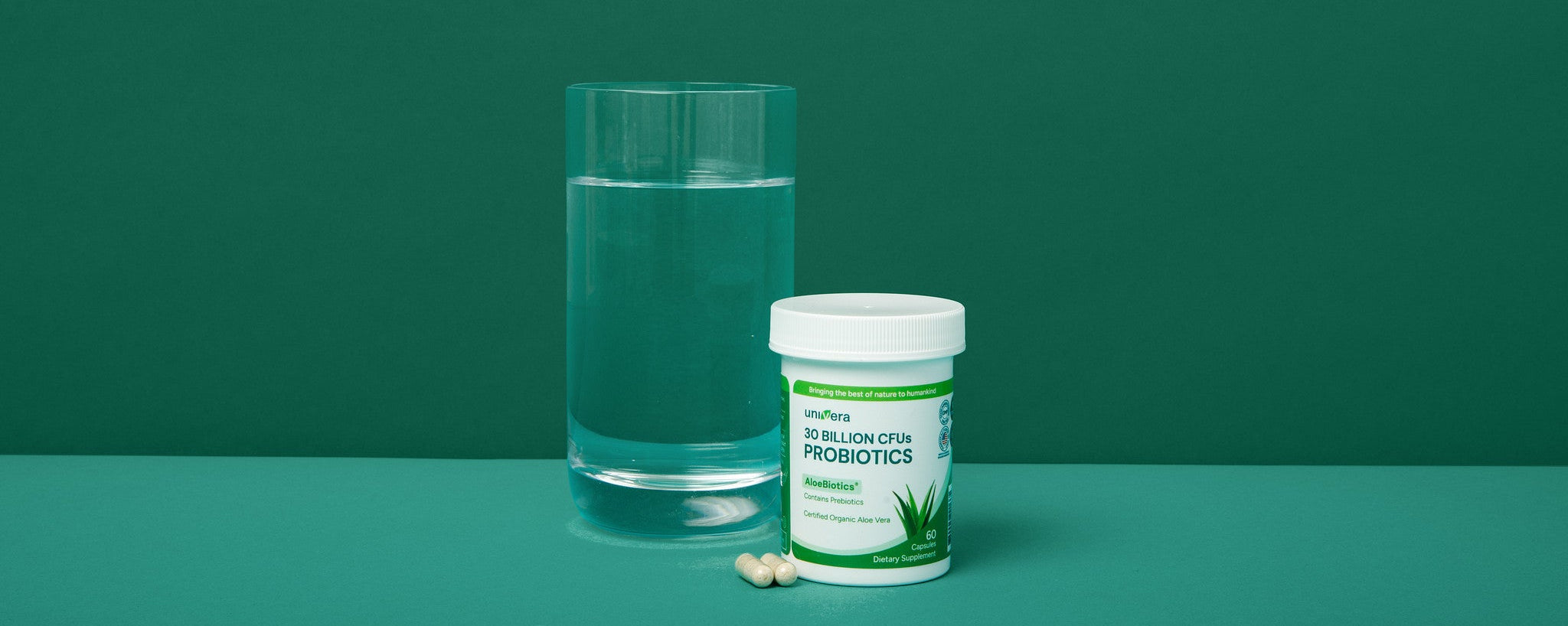 univera aloebiotics, a capsule form of probiotics and prebiotics supplement with 30 billion cfus with a cup of water